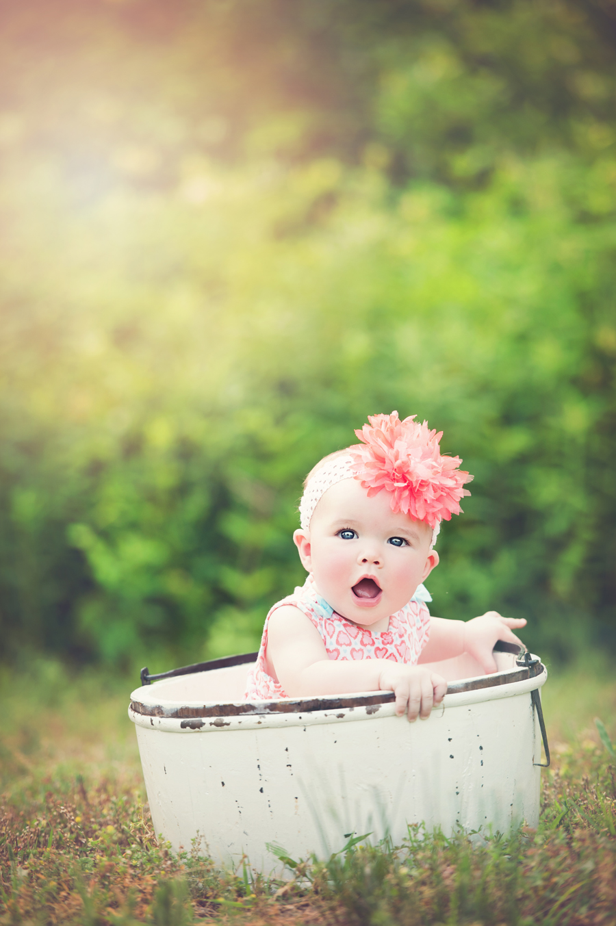 baby in bucket wearing flower headband