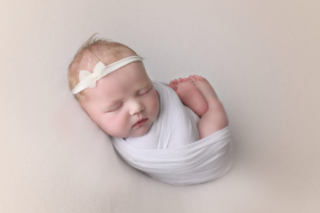 Newborn Baby swaddled in white with headband