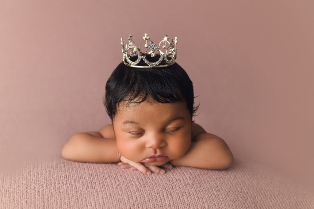 Newborn Baby girl wearing princess crown - tiara on pink blanket