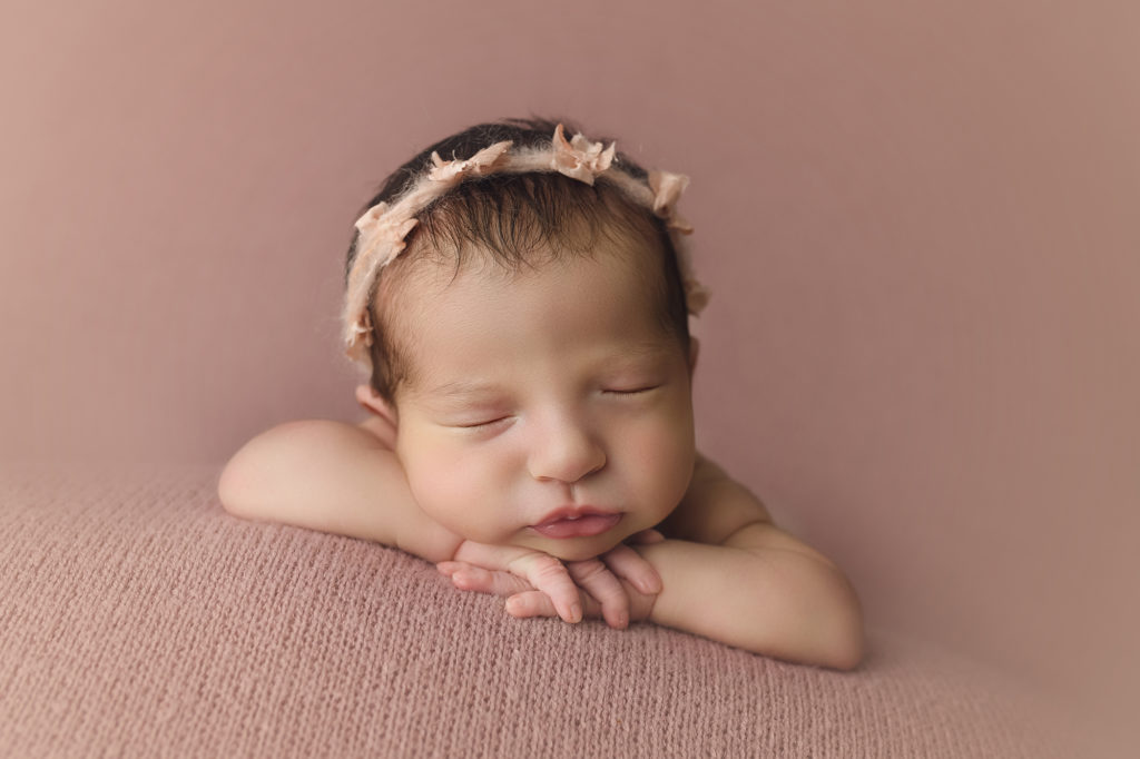 Newborn baby girl on pink blanket with pink ribbons