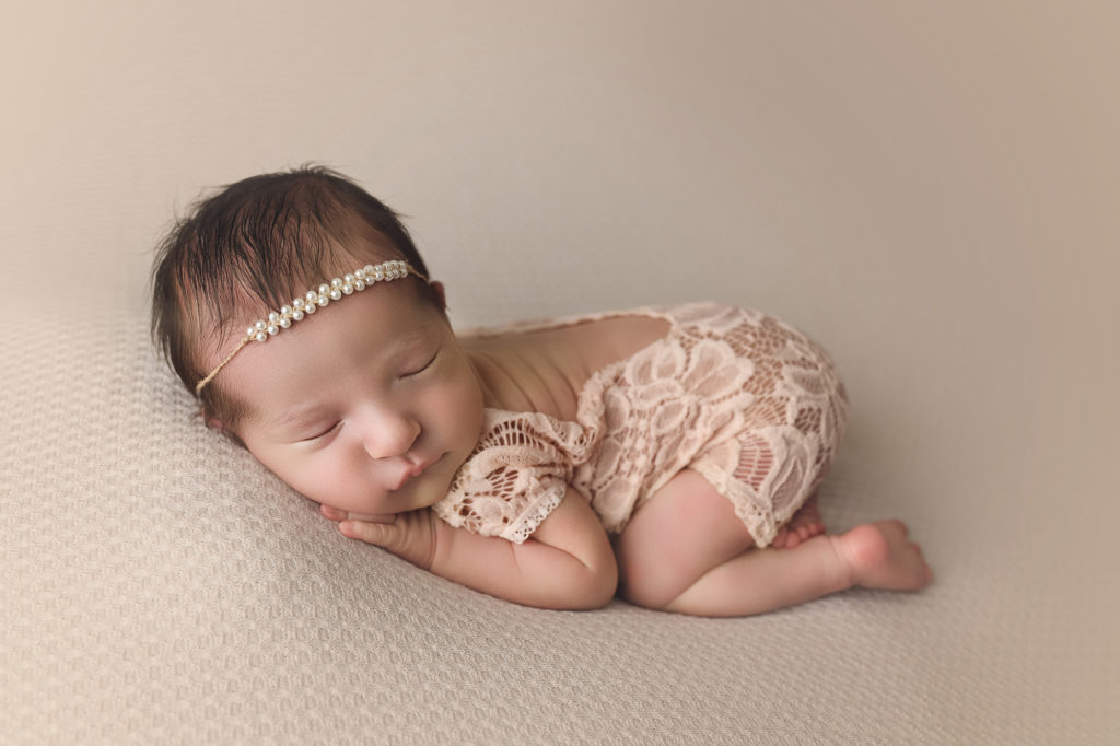 Newborn baby girl wearing pearls in pink lace