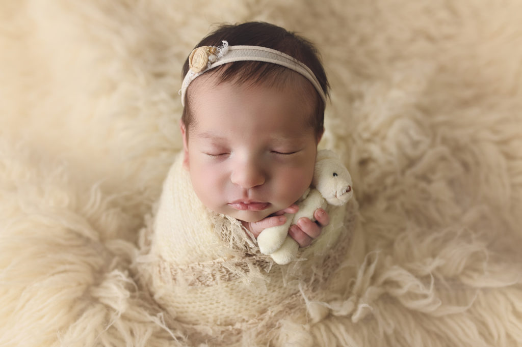 Newborn baby girl holding teddy bear