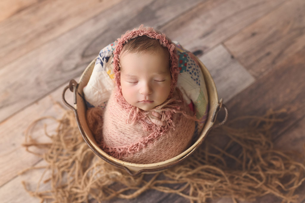Newborn Baby girl in Pink wrap and bonnet in bucket