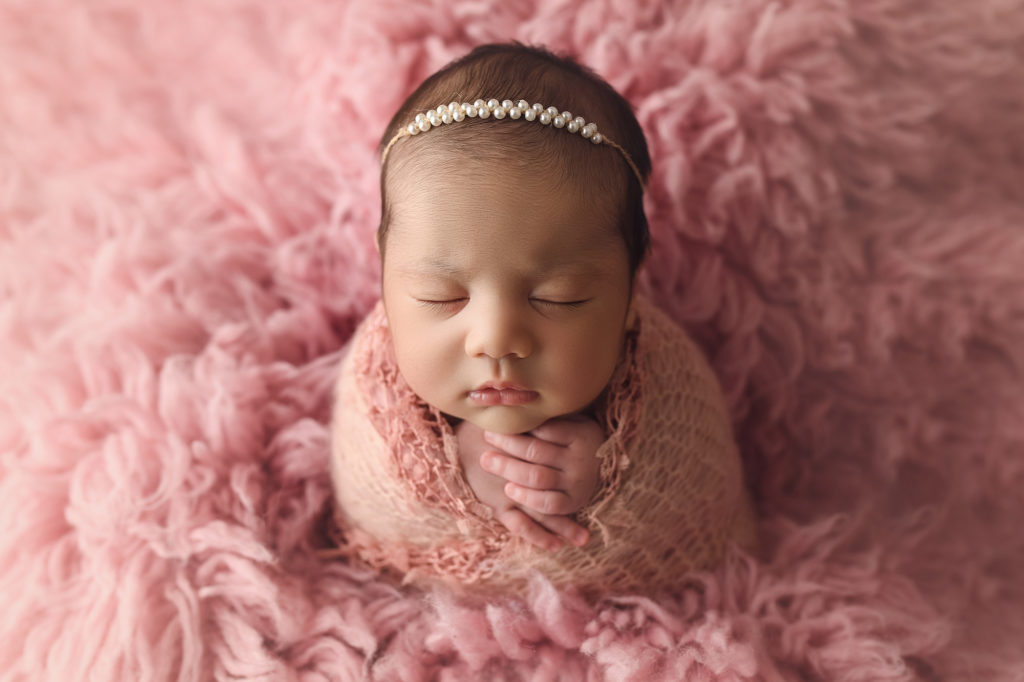 Newborn Baby Girl wrapped in pink on pink fur
