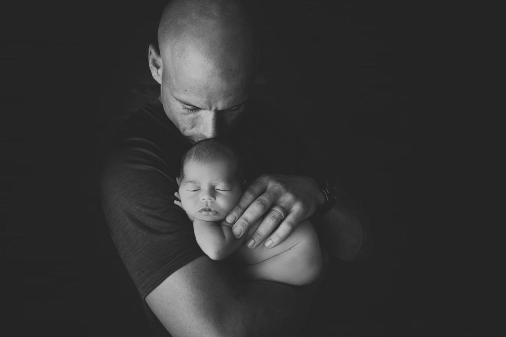 Newborn baby girl in daddy's arms black and white