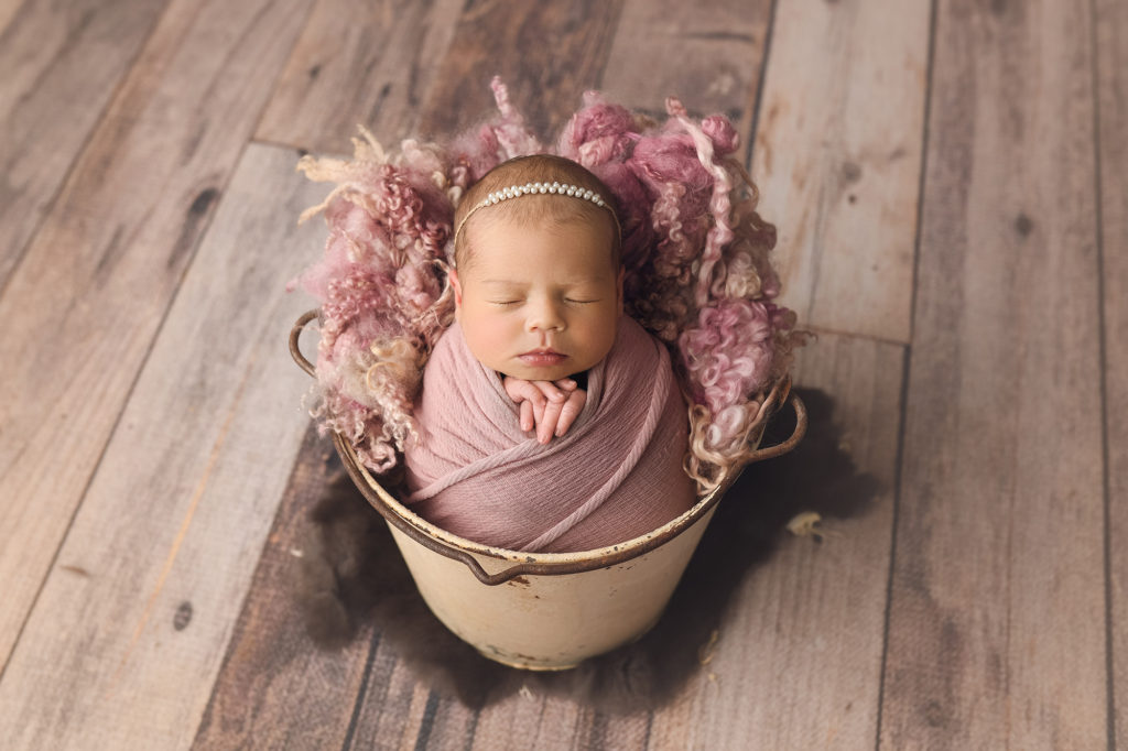 Newborn baby girl in bucket with pink blanket