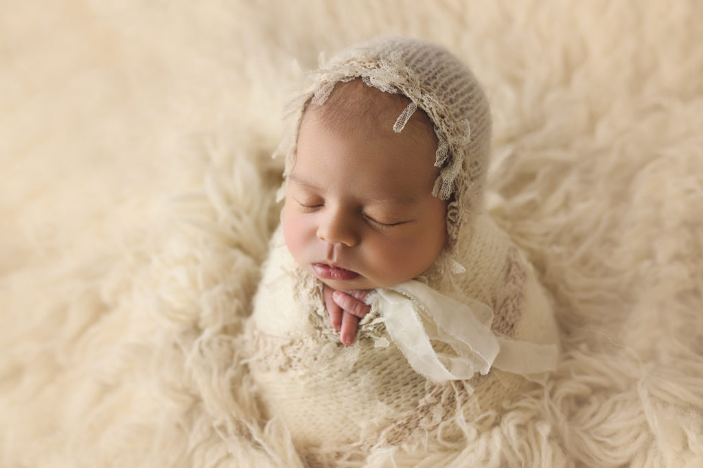 Newborn Baby Girl on white fur with white hat