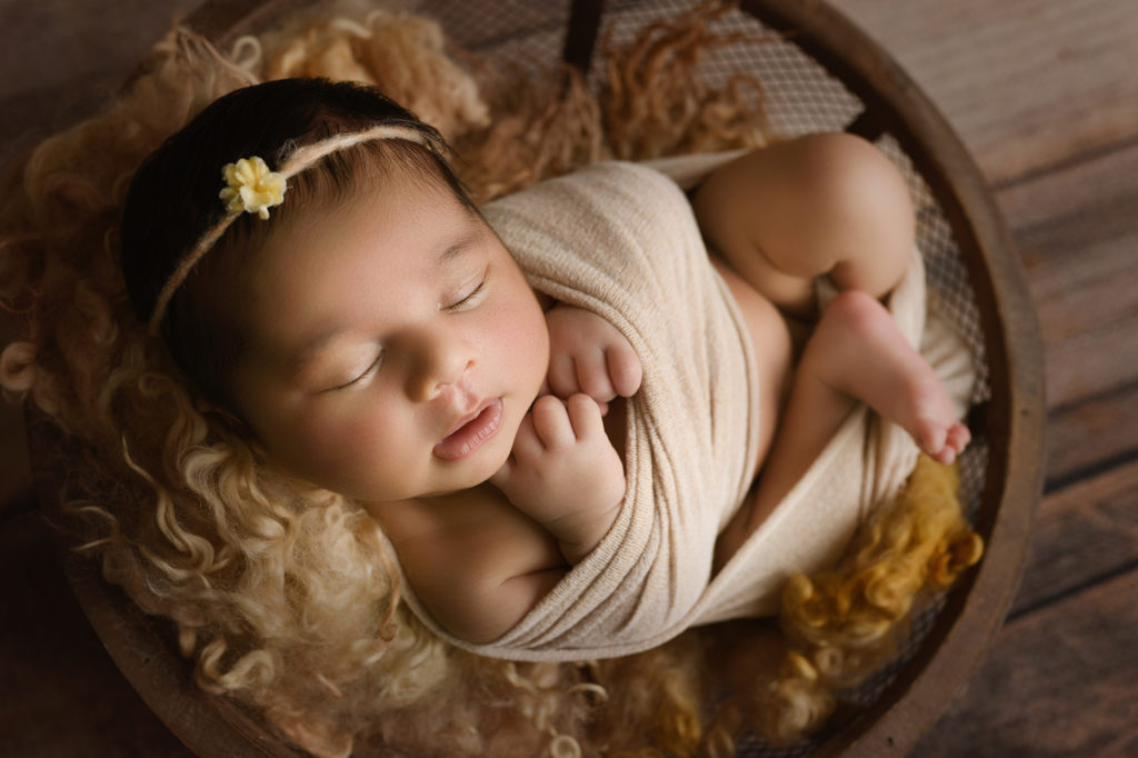 newborn baby girl in bowl with neutral fur