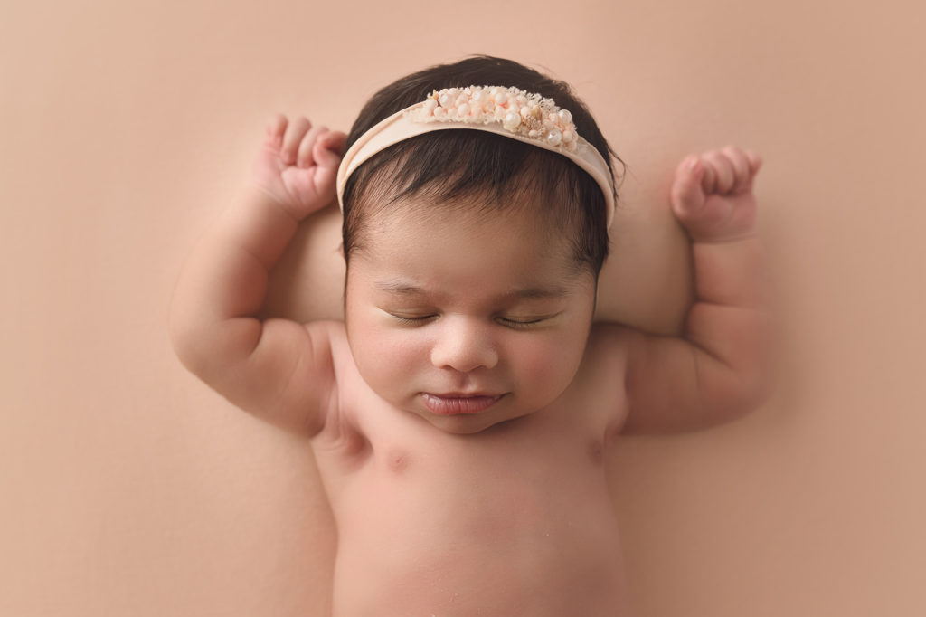 newborn baby girl on peach with pearl headband