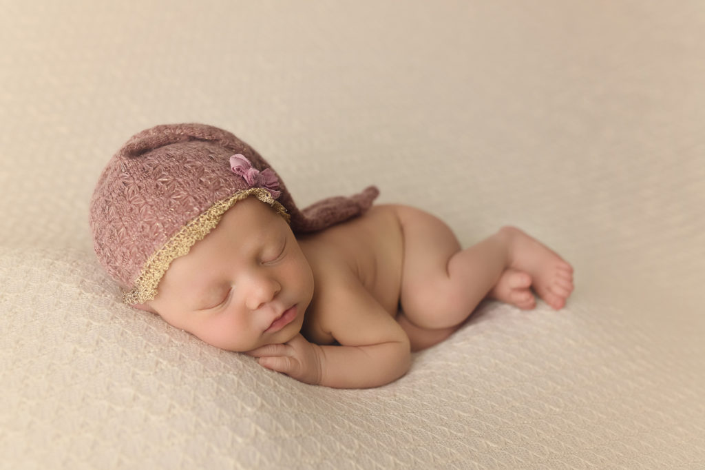 newborn baby girl sleeping with pink sleeper cap
