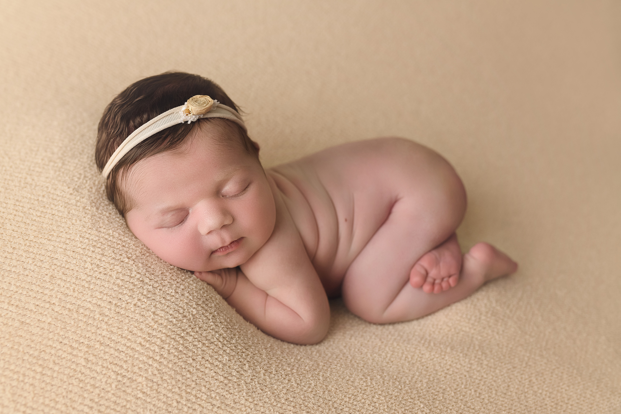 newborn baby girl with cream bow and bum in air