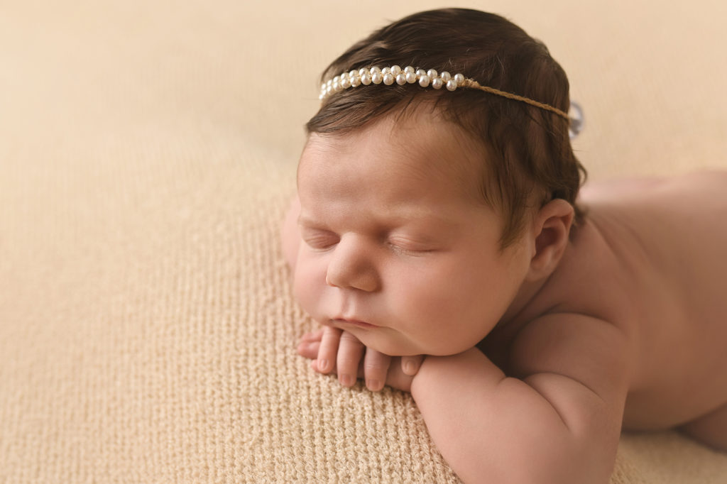 Newborn baby girl with hair wearing pearl headband
