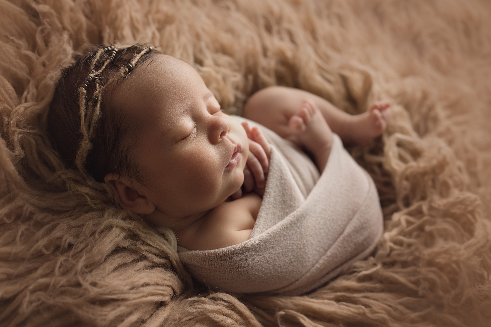 newborn baby girl wrapped tucked in beige fur