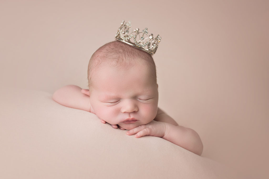 newborn baby girl face forward wearing tiara crown
