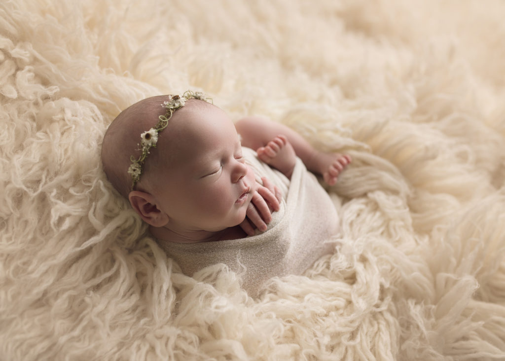 newborn baby girl in white fur and flower headband