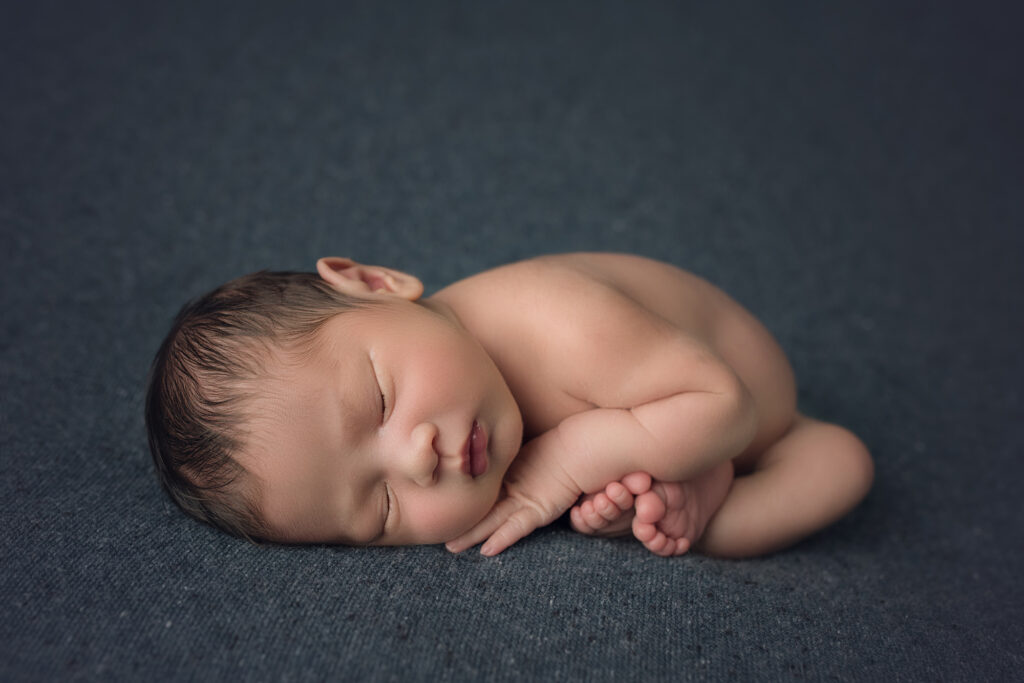 Newborn Baby on navy blue blanket in the taco / womb pose