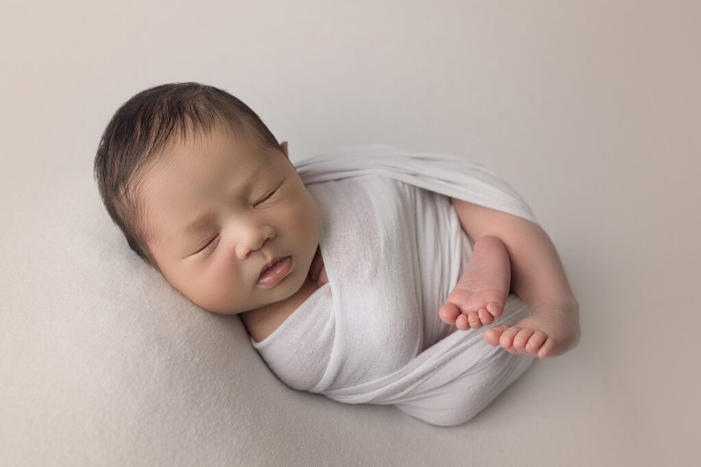 Newborn Baby Boy wrapped in white sleeping
