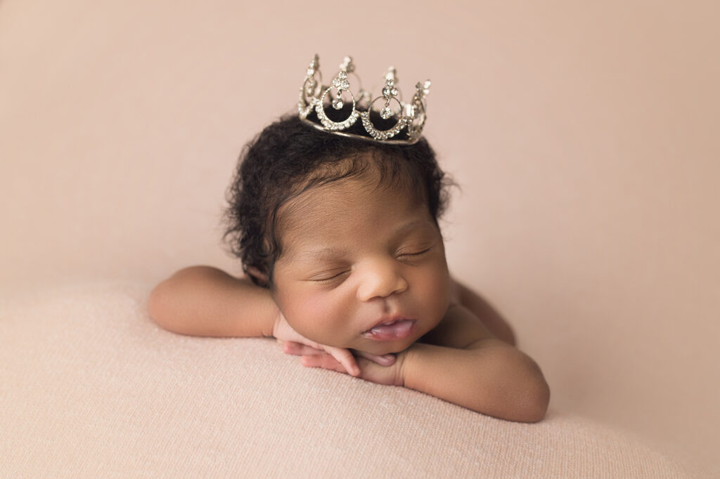 Newborn baby girl dressed as a princess with a tiara on her head