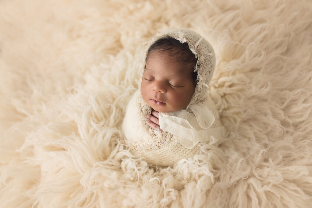 Newborn baby girl on white fur in Potato Pose