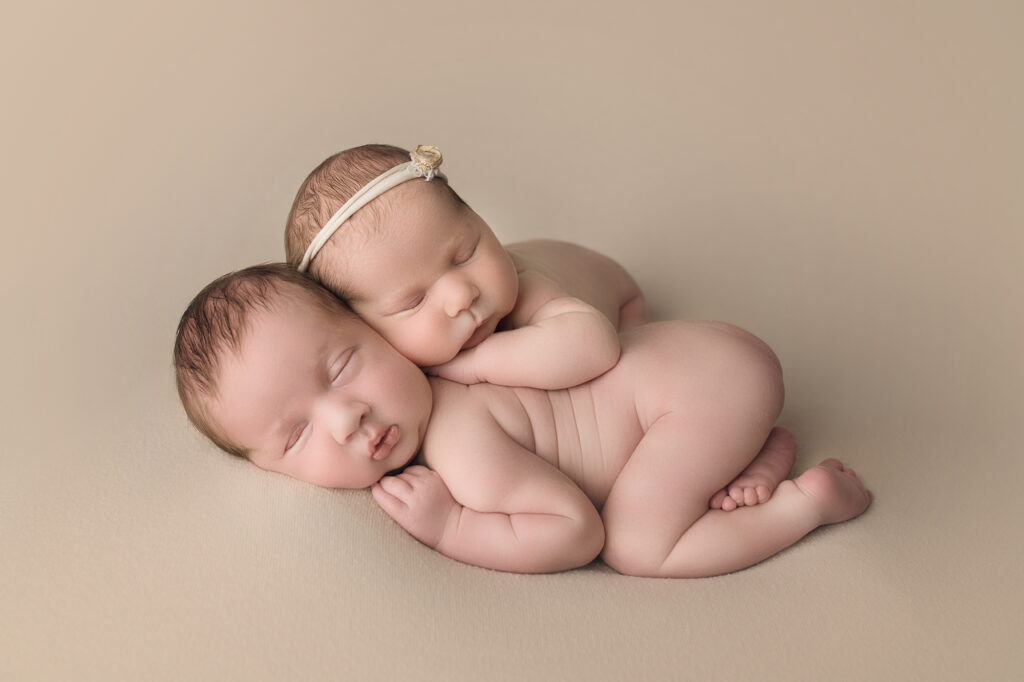 newborn twins bum up on beige blanket
