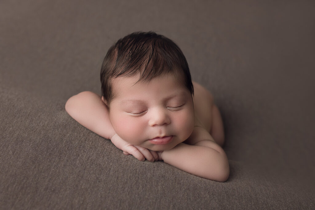 newborn baby boy face forward on brown blanket
