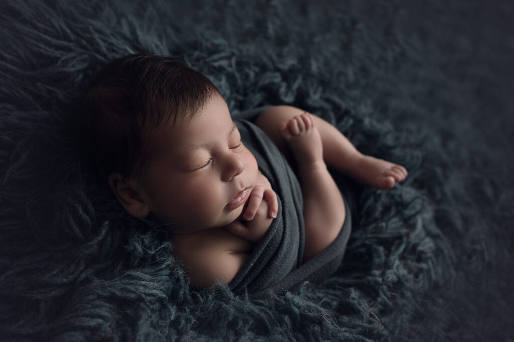 Newborn baby boy wrapped in blue on blue fur