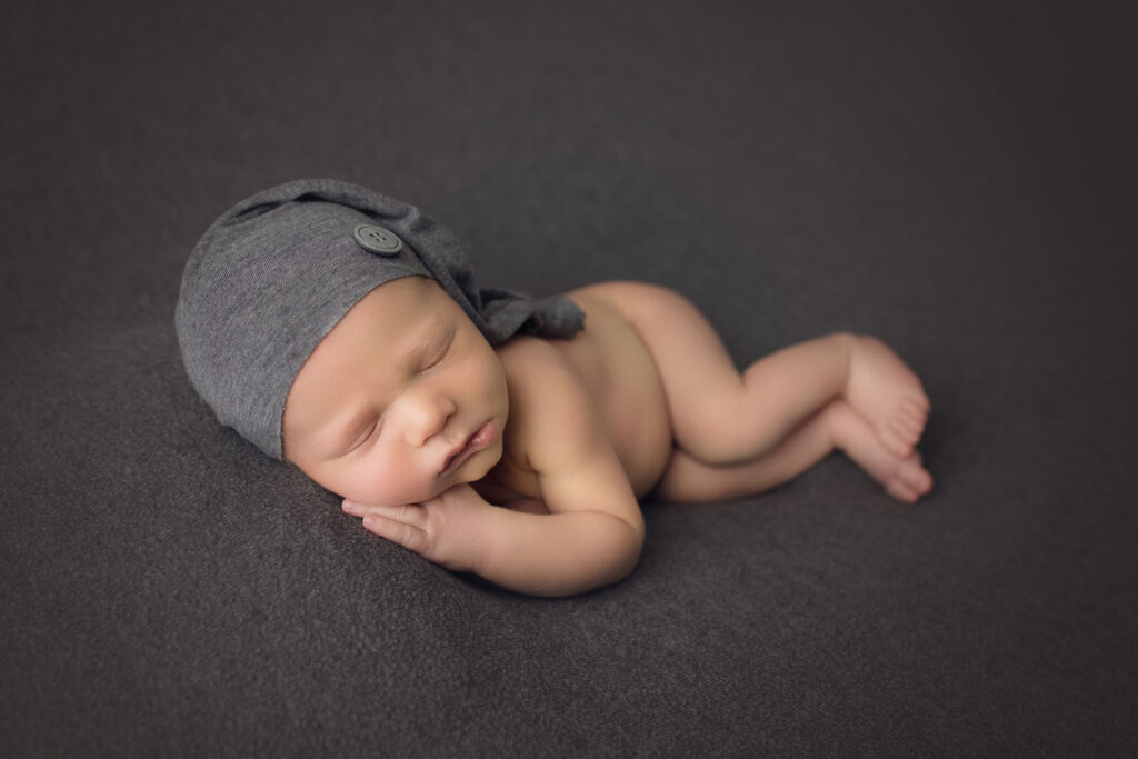 Newborn Baby Boy side lying on gray blanket