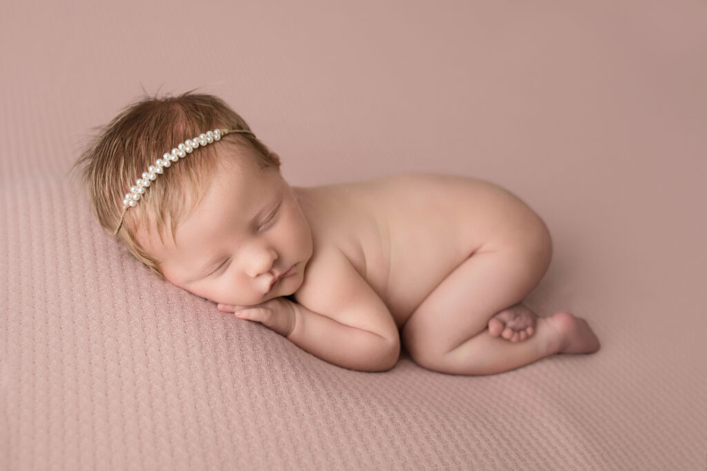 Newborn Baby Girl laying on belly with pearl headband