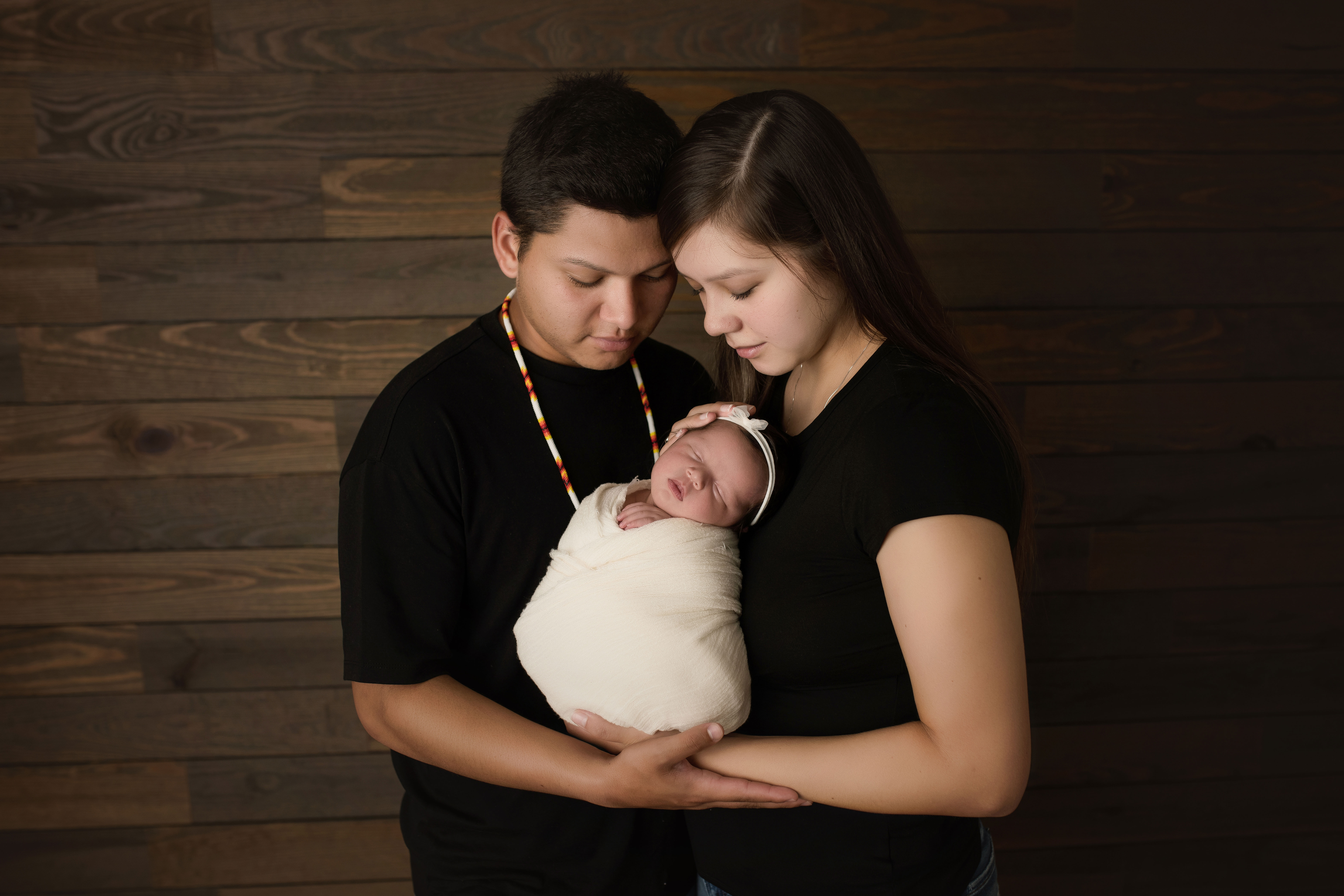 newborn baby girl wrapped in white with mom and dad