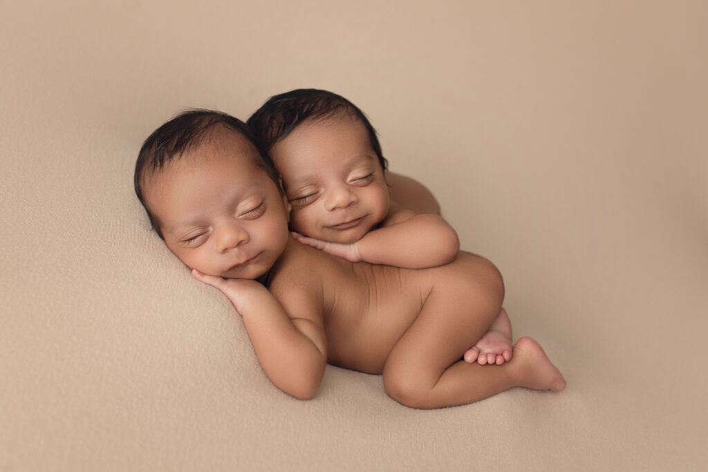 Newborn Twin Boys laying bum up on a beige blanket