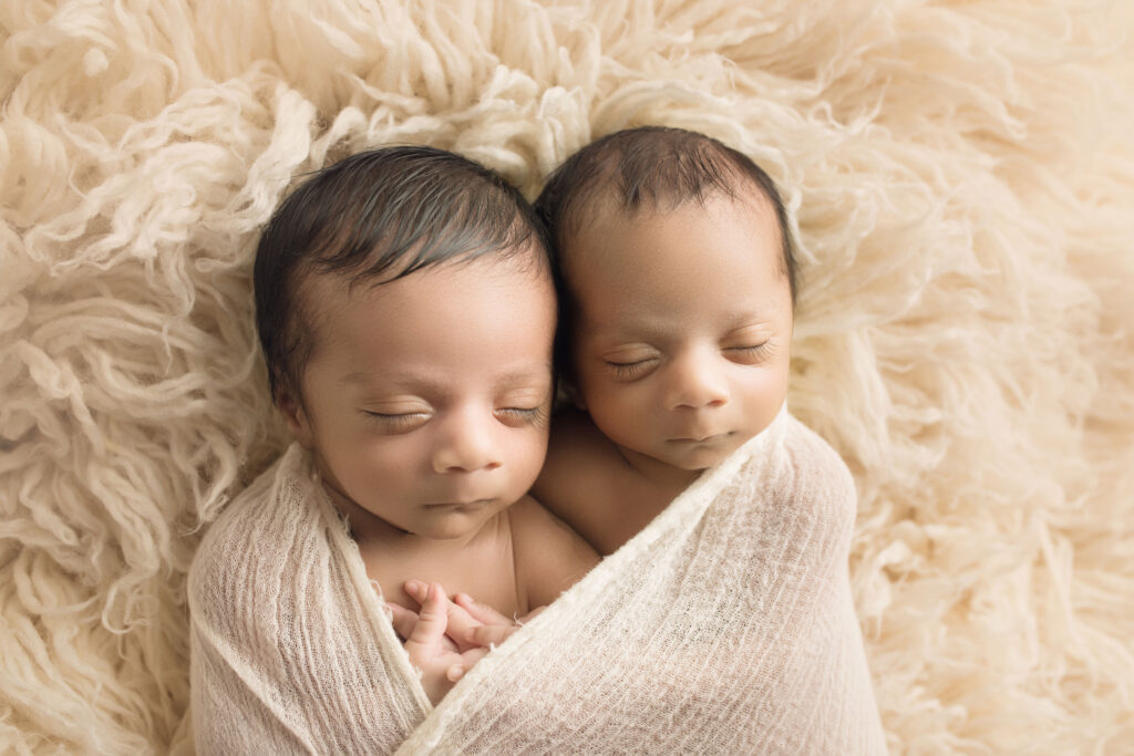 Newborn Twin Boys cuddled together on cream fur