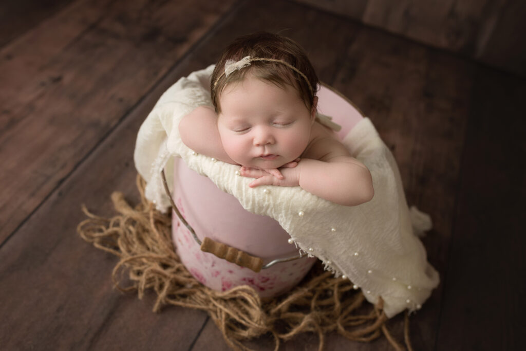 newborn baby girl sleeping in a pink bucket