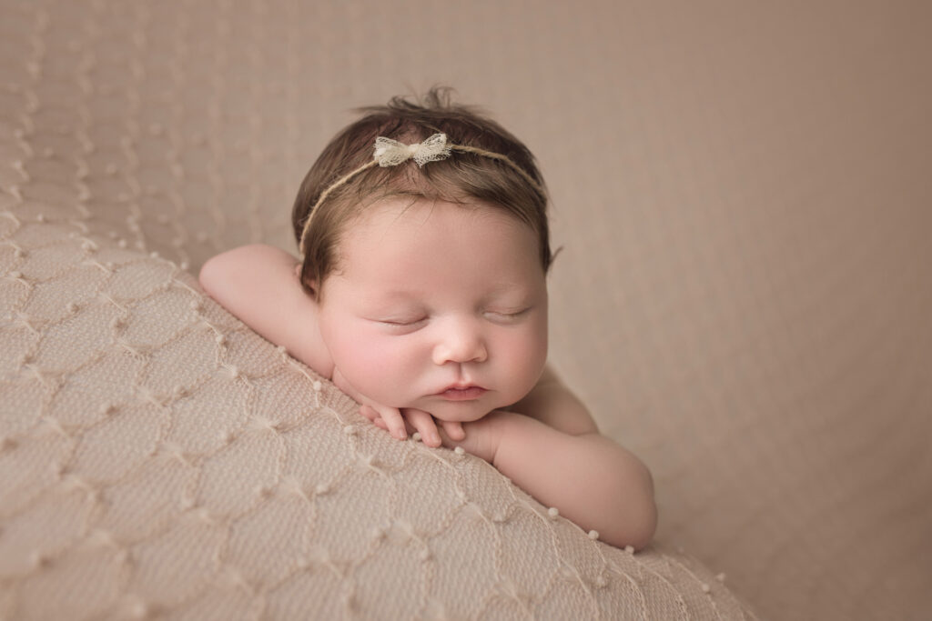newborn baby girl sleeping face forward on a beige knitted blanket newborn photography cary nc