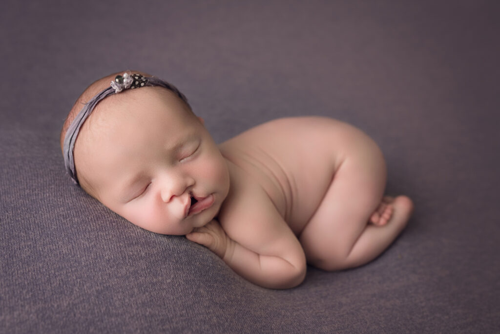 newborn baby girl laying bum up on purple with bum up