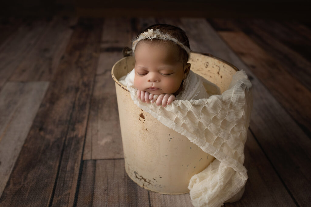 Newborn Baby Girl sleeping in cream bucket