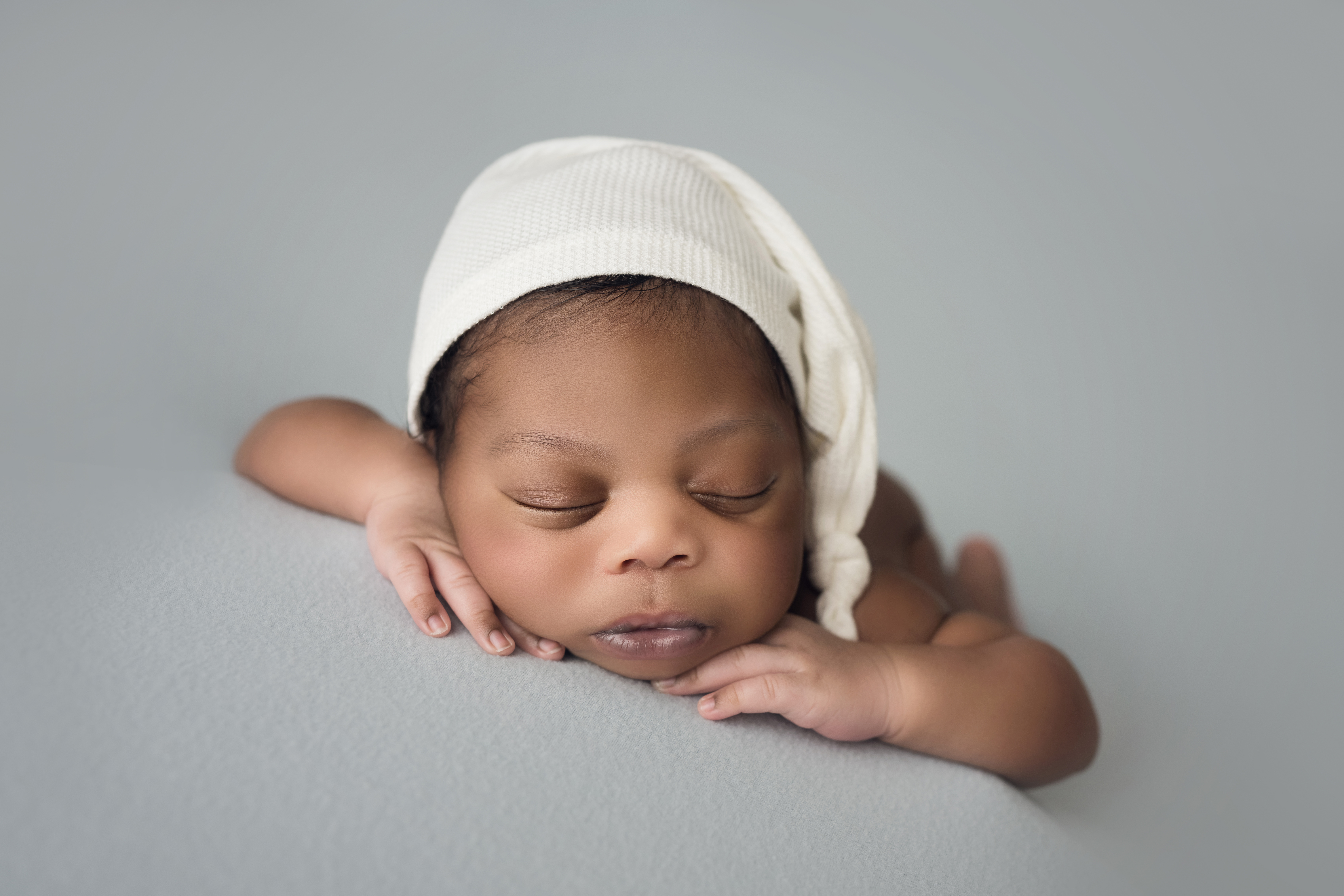 newborn baby boy face forward with white sleepy cap