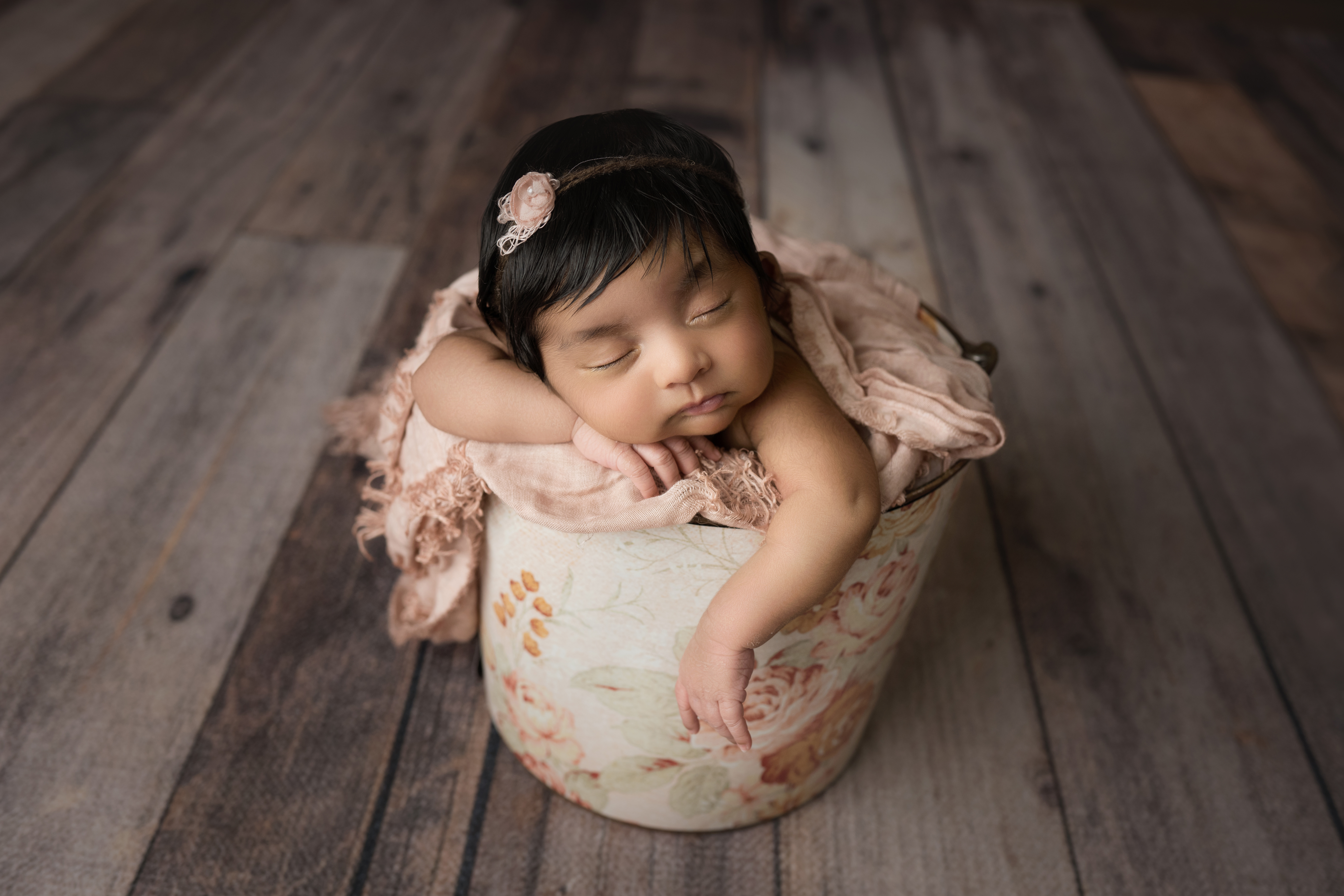 Newborn baby girl face forward in pink floral bucket