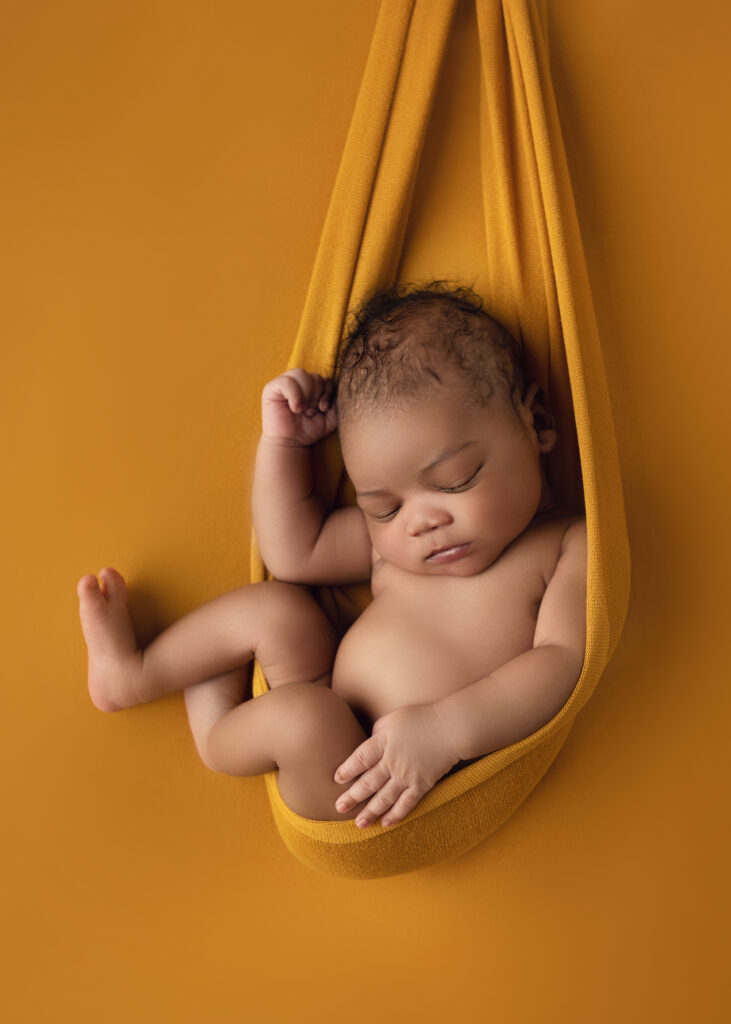 Newborn baby boy in a yellow swing sling