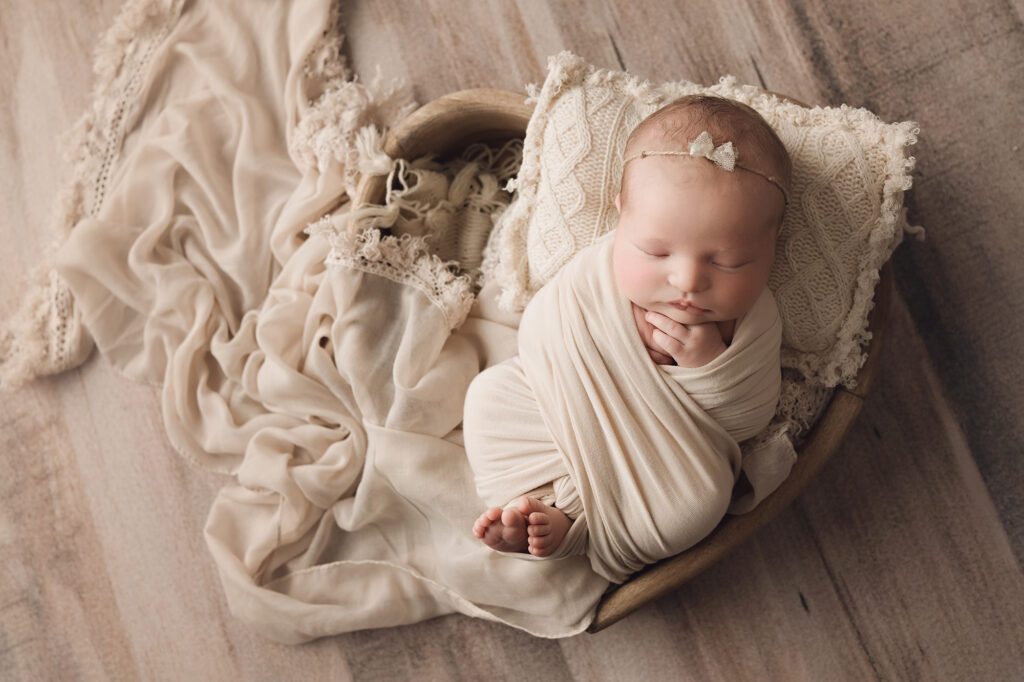 Newborn baby girls wrapped in beige in heart bowl
