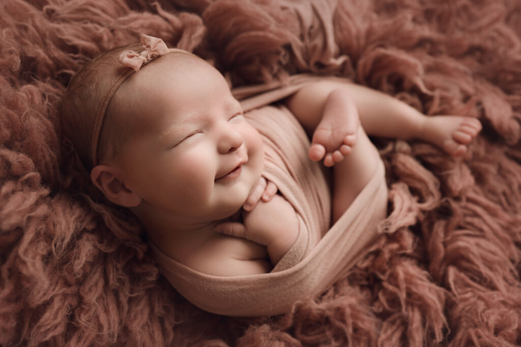 Newborn baby girl on pink fur wrapped in pink and pink headband raleigh newborn photography