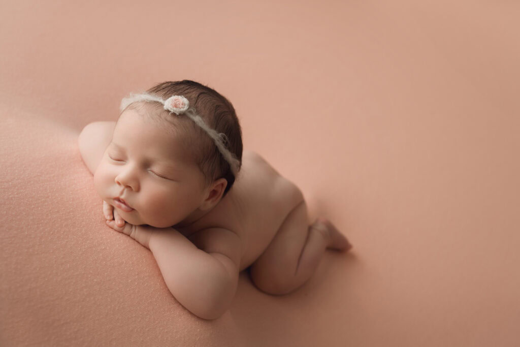 ### Raleigh Newborn Photographer baby girl face forward on pink blanket