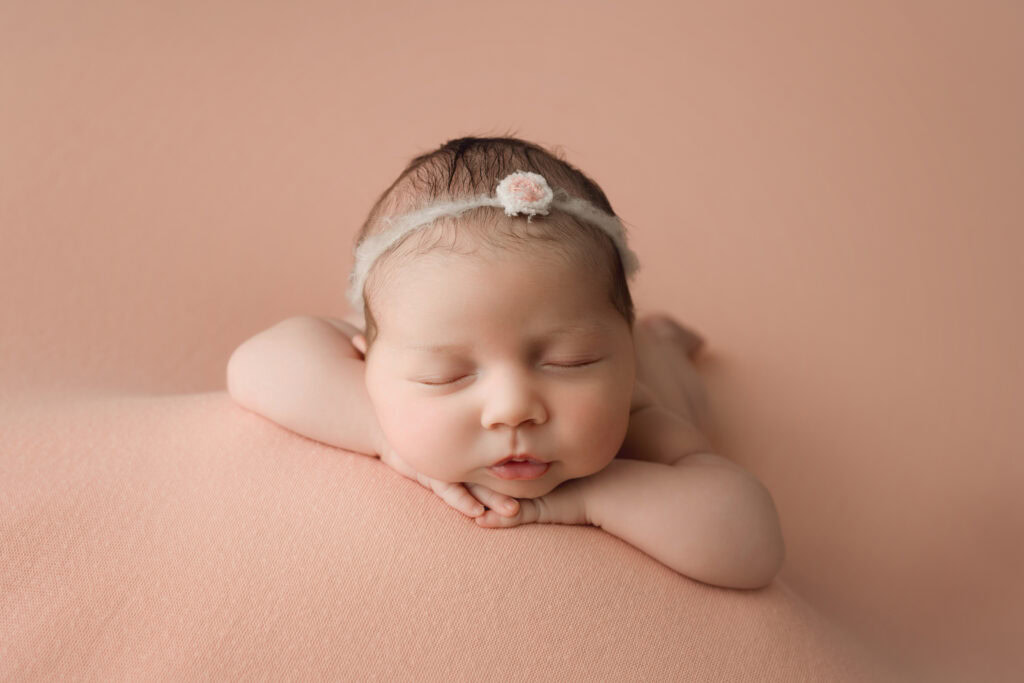 ### Newborn baby girl face forward on pink blanket
