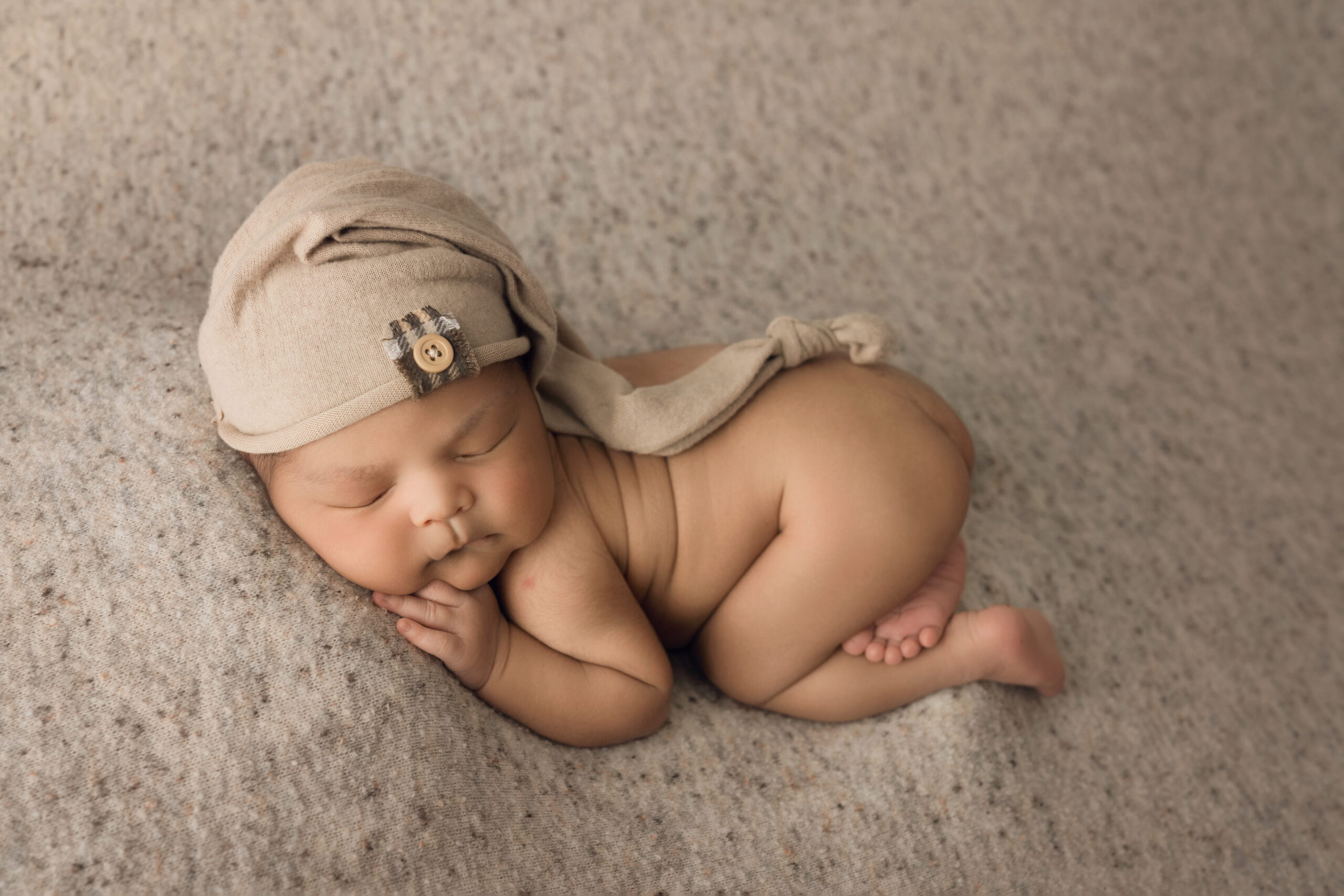 newborn baby boy wearing sleepy hat with bum up sleeping