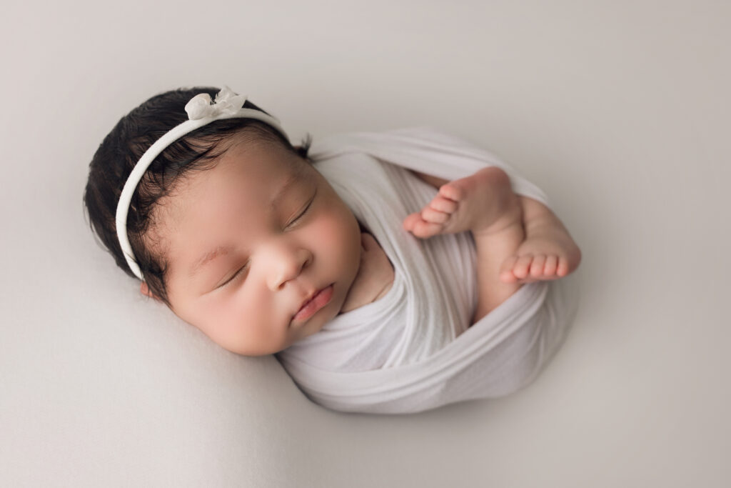 Newborn Baby Girl wrapped in white with a white bow