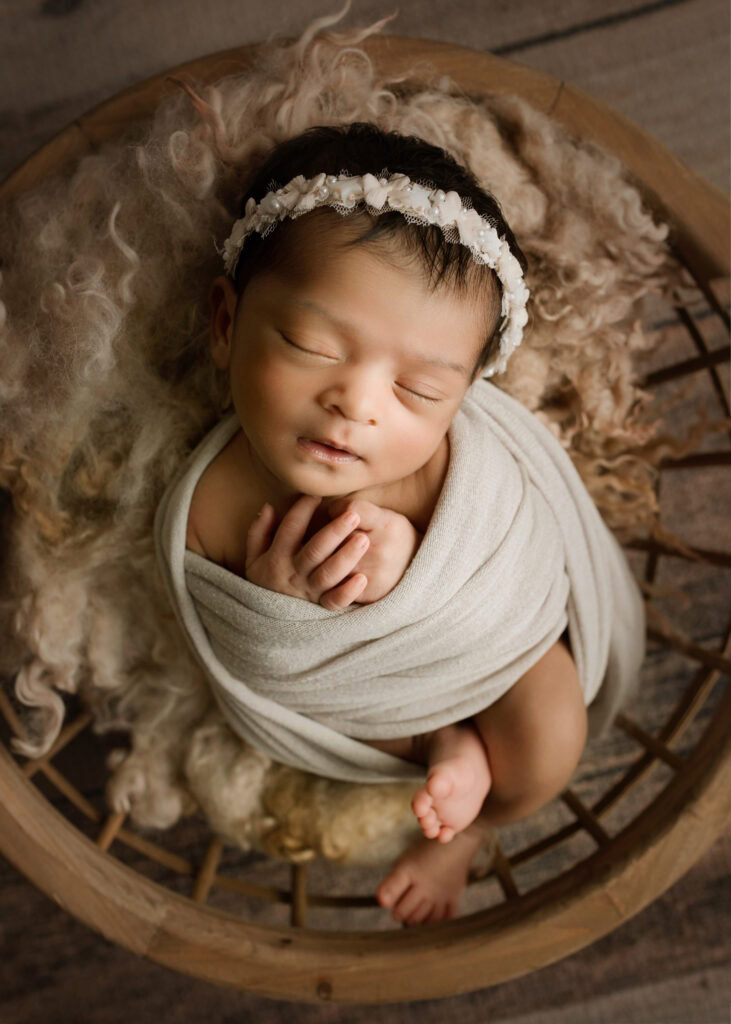 Newborn Baby Girl wrapped in a cream wrap with a pearl headband in a bowl Holly Springs NC Newborn Photographer