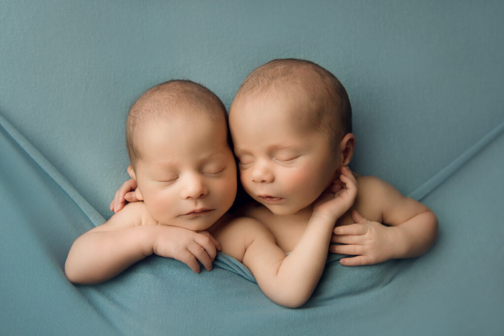 Newborn Baby twin boys cuddled in a blue blanket