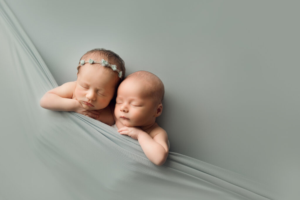 Newborn twins resting on pastel green blanket in a professional baby photography session