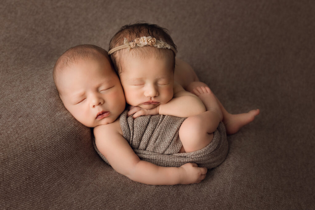 Adorable newborn twins cuddling on a soft brown blanket, showcasing professional Newborn Photography. Double the Joy: Newborn Photography for Twins in Raleigh