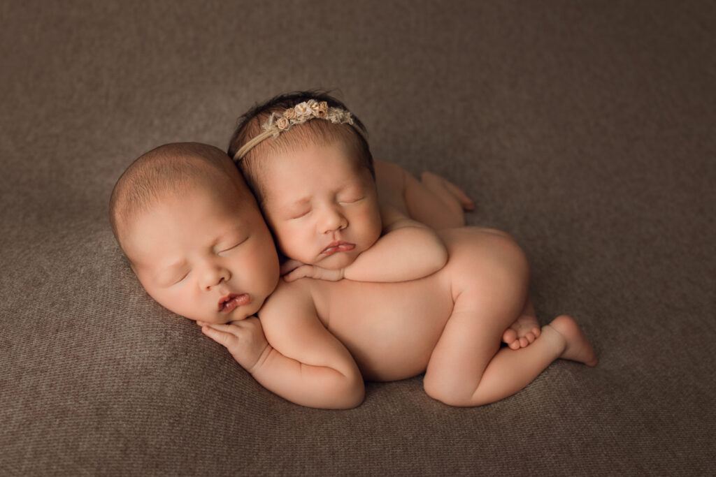 Soft newborn twin siblings sleeping peacefully on textured brown background, capturing adorable infant photography, Newborn Photography, Baby Portraits.